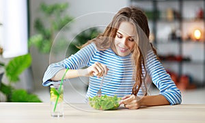 Healthy eating. happy young girl eating salad in morning in kitchen