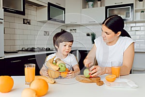 Healthy Eating. mom with baby eating fruits in the kitchen