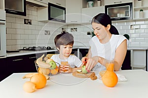 Healthy Eating. mom with baby eating fruits in the kitchen