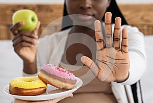 Healthy Eating During Pregnancy. Black Pregnant Lady Refusing Unhealthy Donuts, Choosing Apple