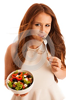 Healthy eating - woman eats a bowl of greek salad isolated over