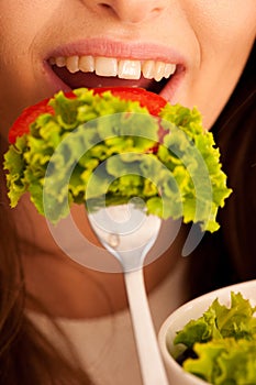 Healthy eating - woman eats a bowl of greek salad isolated over