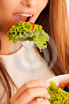 Healthy eating - woman eats a bowl of greek salad isolated over