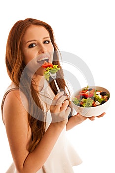 Healthy eating - woman eats a bowl of greek salad isolated over