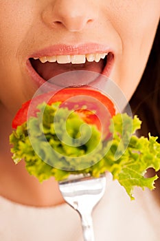 Healthy eating - woman eats a bowl of greek salad isolated over