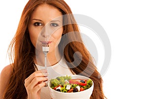 Healthy eating - woman eats a bowl of greek salad isolated over