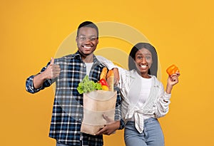 Healthy eats, modern ordering products online. Happy young african american husband and wife hold paper bags