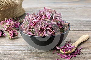 Healthy echinacea flowers in black bowl and sack of dry coneflowers on background. Herbal medicine photo