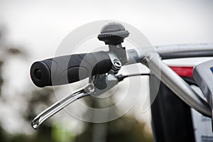 Bicycle handlebar, brake lever and bel close-up over blurred avenue