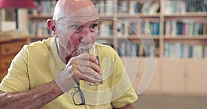 Healthy, elderly or man drinking water for wellness or hydration to relax with arthritis in a library. Parkinson, tremor