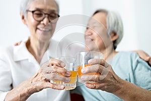 Healthy elderly sibling drinking vitamin C,orange juice and clinking glasses at home,senior people with effervescent vitamin C,