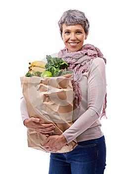 Healthy equals happy. Studio portrait of a mature woman holding a brown paper bag filled with fruit and vegetables.