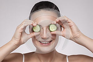 Healthy eyes. Beautiful healthy caucasian middle aged shirtless woman holding slices of cucumber in front of her eyes while