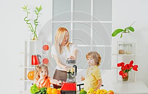 Healthy family food. Mother daughter and little son preparing healthy smoothie in the modern kitchen.