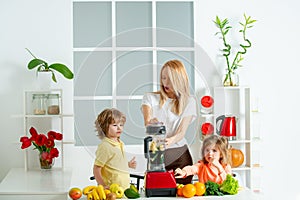 Healthy family food. Mother daughter and little son preparing healthy smoothie in the modern kitchen.