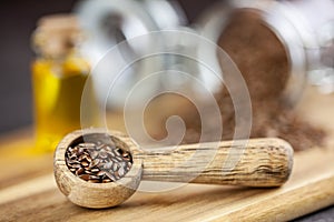 Healthy fat - Linseed on woden spoon, linseed and linseed oil in bootle in the background photo