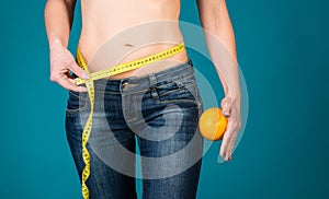 Healthy female body with orange and measuring tape. Healthy fitness and eating lifestyle concept.