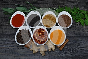 Fresh herbs and spices in dishes with on a rustic wood background, overhead view photo