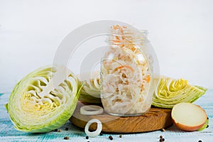 Healthy fermented vegetables in glass jars on a wooden background.