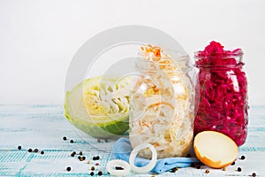 Healthy fermented vegetables in glass jars on a wooden background.