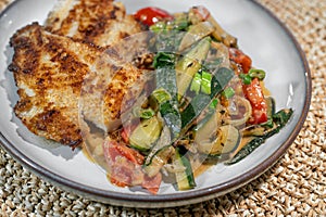 Healthy fish dish of fried redfish fillet with Mediterranean vegetables such as zucchini, tomatoes and leek in sauce, high protein