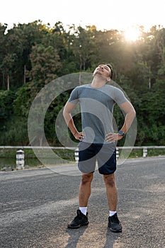 A healthy, fit Asian man stretching his neck, warming up before jogging in the morning