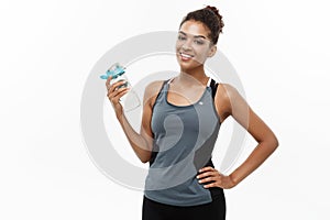 Healthy and fitness concept - beautiful African American girl in sport clothes holding water bottle after workout