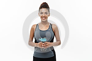 Healthy and fitness concept - beautiful African American girl in sport clothes holding water bottle after workout