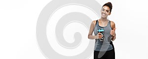 Healthy and Fitness concept - beautiful African American girl in sport clothes holding water bottle after workout