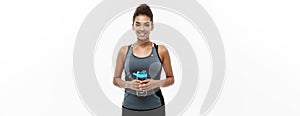 Healthy and Fitness concept - beautiful African American girl in sport clothes holding water bottle after workout