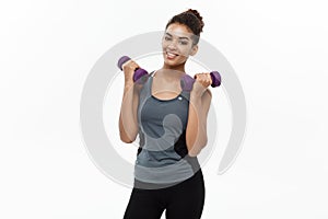 Healthy and Fitness concept - Beautiful American African lady in fitness clothes workout with dumbbell. Isolated on