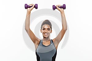 Healthy and Fitness concept - Beautiful American African lady in fitness clothes workout with dumbbell. Isolated on