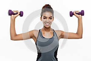 Healthy and Fitness concept - Beautiful American African lady in fitness clothes workout with dumbbell. Isolated on