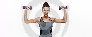 Healthy and Fitness concept - Beautiful American African lady in fitness clothes workout with dumbbell. Isolated on