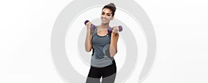 Healthy and Fitness concept - Beautiful American African lady in fitness clothes workout with dumbbell. Isolated on