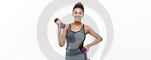 Healthy and Fitness concept - Beautiful American African lady in fitness clothes workout with dumbbell. Isolated on