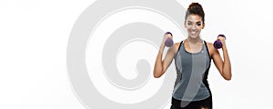 Healthy and Fitness concept - Beautiful American African lady in fitness clothes workout with dumbbell. Isolated on