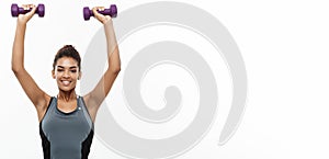 Healthy and Fitness concept - Beautiful American African lady in fitness clothes workout with dumbbell. Isolated on