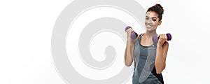 Healthy and Fitness concept - Beautiful American African lady in fitness clothes workout with dumbbell. Isolated on