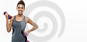 Healthy and Fitness concept - Beautiful American African lady in fitness clothes workout with dumbbell. Isolated on