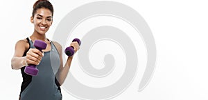 Healthy and Fitness concept - Beautiful American African lady in fitness clothes workout with dumbbell. Isolated on