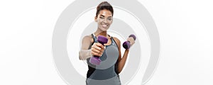 Healthy and Fitness concept - Beautiful American African lady in fitness clothes workout with dumbbell. Isolated on