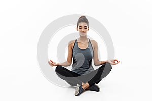 Healthy and Fitness concept - Beautiful American African lady in fitness clothing doing yoga and meditation. Isolated on