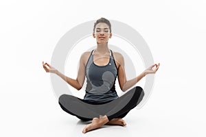 Healthy and Fitness concept - Beautiful American African lady in fitness clothing doing yoga and meditation. Isolated on