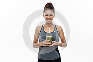 Healthy and Fitness concept - Beautiful American African lady in fitness clothing drinking healthy vegetable drink