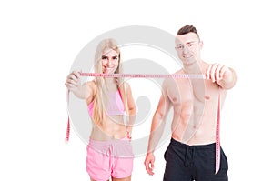 Healthy fitness couple holding meter or centimeter