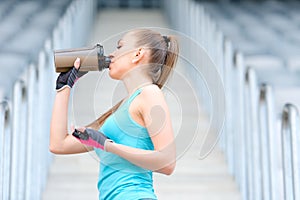 Healthy fitness girl drinking protein shake. Woman drinking sports nutrition beverage while working out