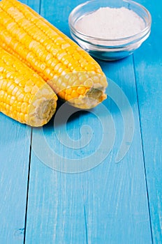 Healthy food. Appetizing boiled corn with salt on a blue background. Copy space