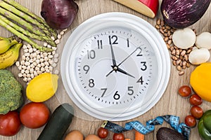 Healthy food around a circular clock with a wooden background