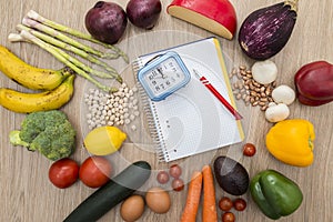 Healthy food around a notebook with a clock on top